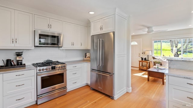 kitchen featuring recessed lighting, stainless steel appliances, white cabinetry, light wood-style floors, and decorative backsplash