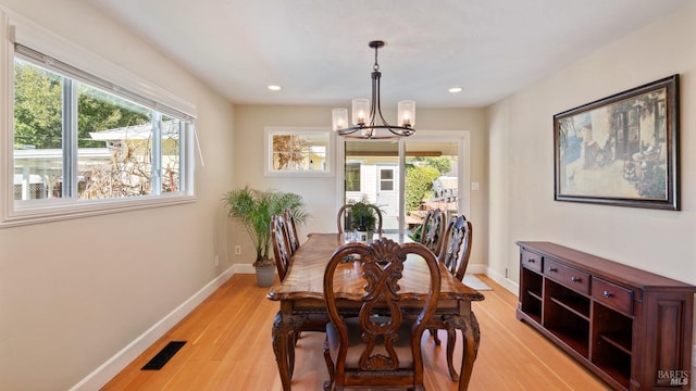 dining space featuring visible vents, a notable chandelier, light wood-style flooring, and baseboards