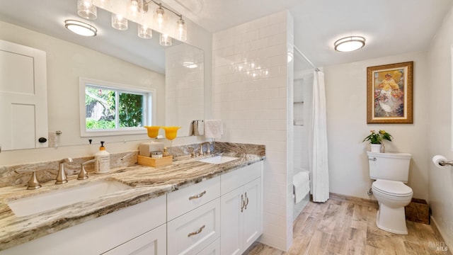 bathroom with double vanity, a sink, toilet, and wood finished floors