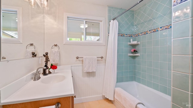 full bathroom with a wainscoted wall, shower / bathtub combination with curtain, tile patterned flooring, and vanity