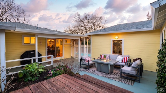 deck at dusk with grilling area, an outdoor living space with a fire pit, and fence