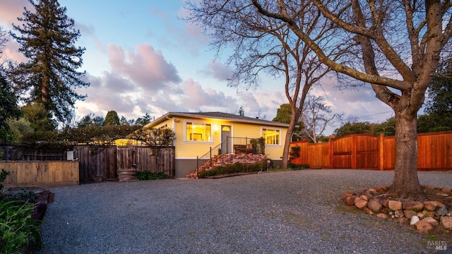 view of front facade featuring gravel driveway, a gate, and fence