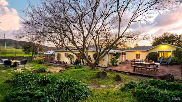 back of property with a fire pit, fence, and a deck