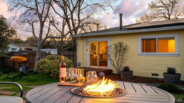 back of property at dusk with crawl space, fence, and a fire pit