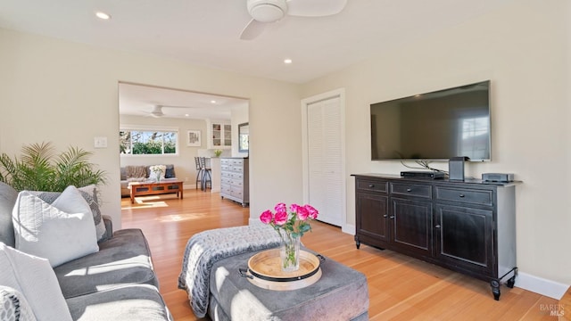 living room featuring light wood-style flooring, baseboards, and ceiling fan