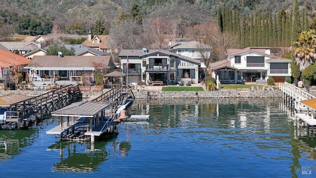 view of dock with a residential view, a water view, and a wooded view