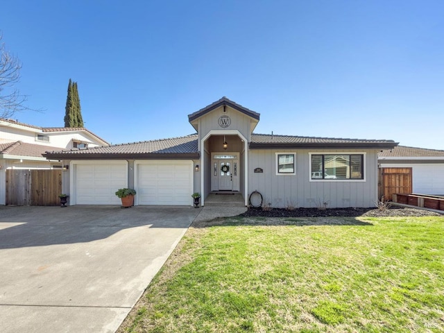 view of front of property with an attached garage, fence, a front lawn, and concrete driveway