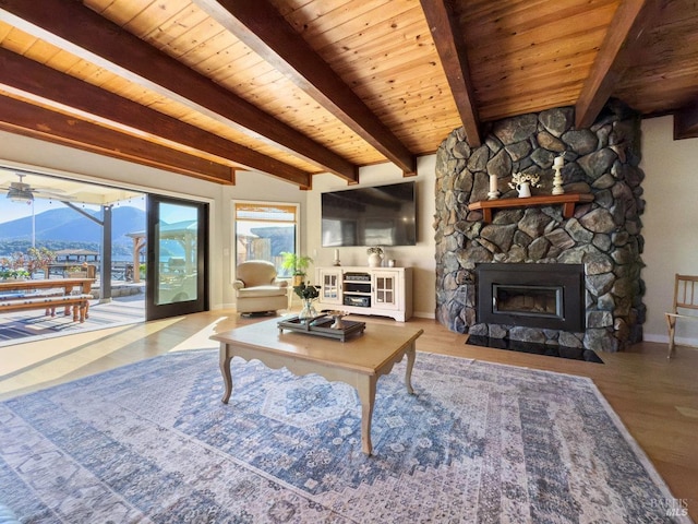 living area featuring baseboards, wood ceiling, wood finished floors, a fireplace, and beam ceiling