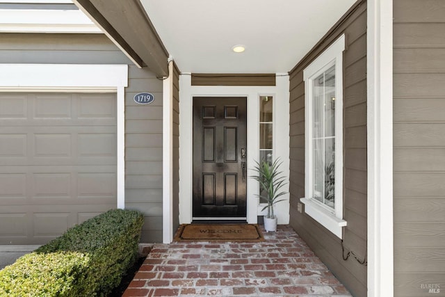 view of exterior entry with a garage and covered porch