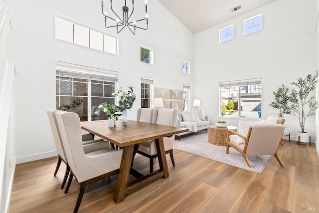 dining room with light wood-style floors, a chandelier, visible vents, and baseboards