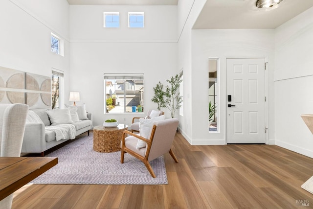 living room with a high ceiling, wood finished floors, and baseboards