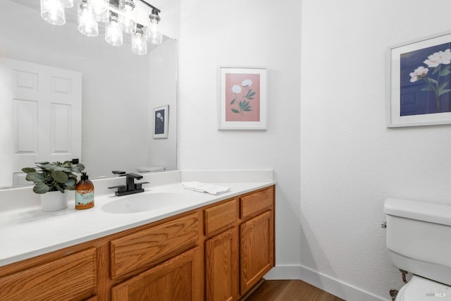 bathroom featuring baseboards, vanity, toilet, and wood finished floors