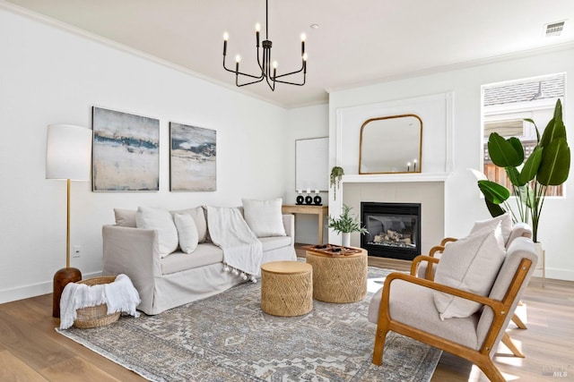 living area with baseboards, visible vents, a tiled fireplace, wood finished floors, and crown molding