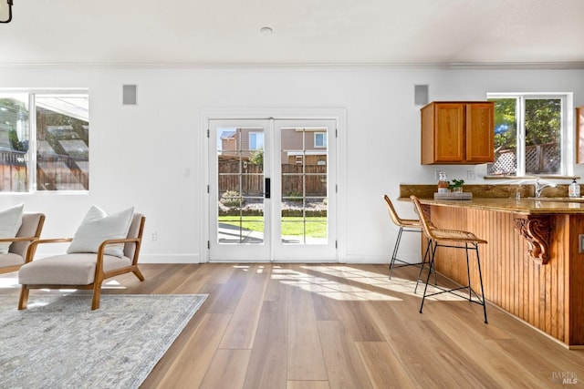 interior space with light wood finished floors, brown cabinetry, a breakfast bar, and crown molding