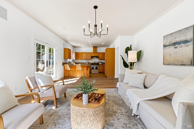 living room featuring recessed lighting, crown molding, french doors, light wood finished floors, and an inviting chandelier