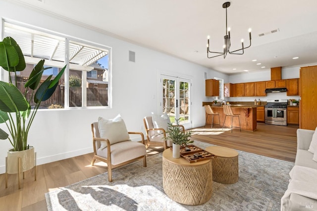 living room featuring french doors, a notable chandelier, visible vents, light wood-style floors, and baseboards