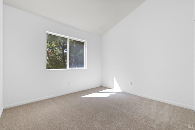 spare room with baseboards, vaulted ceiling, and carpet flooring