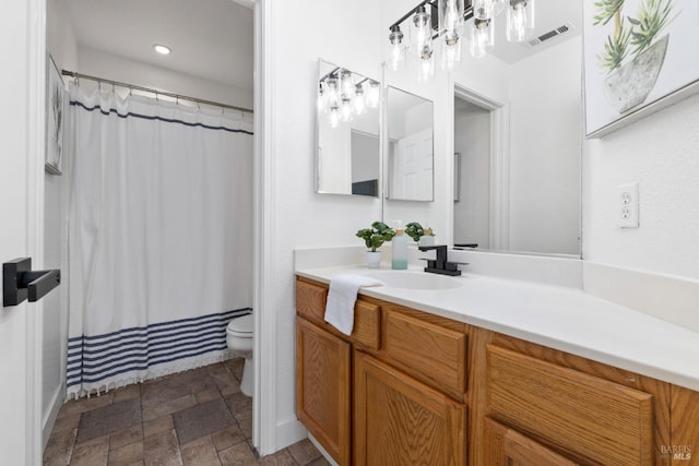 bathroom with stone tile floors, recessed lighting, visible vents, toilet, and vanity