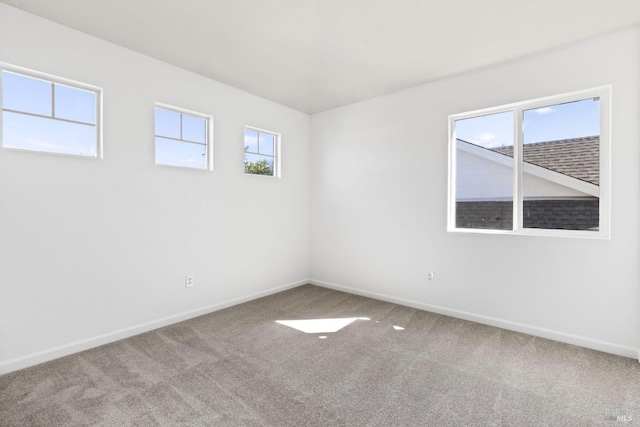 empty room featuring carpet and baseboards