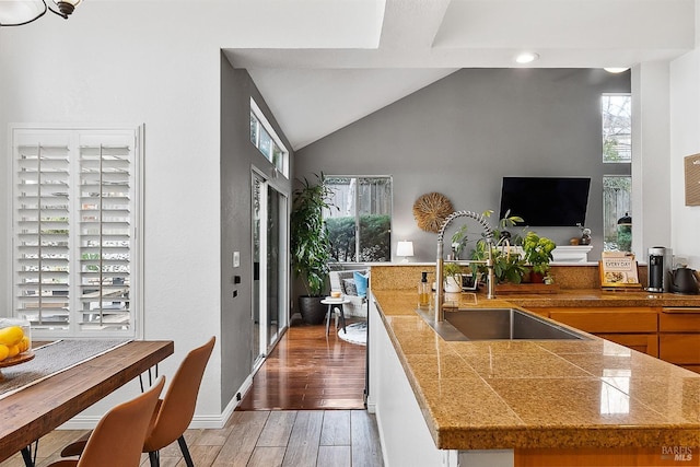 kitchen with tile counters, recessed lighting, lofted ceiling, light wood finished floors, and a sink