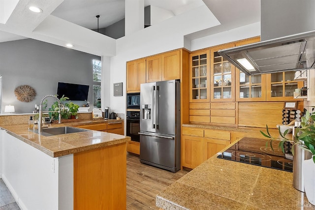 kitchen featuring glass insert cabinets, exhaust hood, a sink, black appliances, and tile countertops