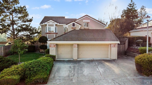 traditional-style home with concrete driveway, stucco siding, a tile roof, fence, and a front yard