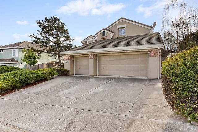 view of front of home featuring an attached garage, stucco siding, concrete driveway, and a tiled roof