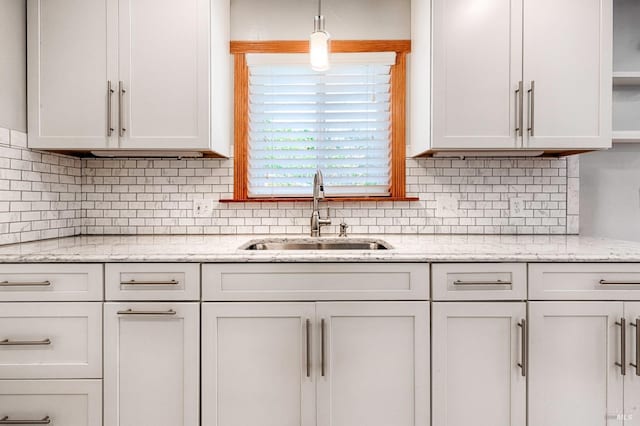 kitchen featuring a sink, light stone countertops, white cabinetry, open shelves, and backsplash