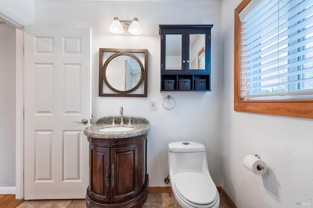 bathroom with toilet, baseboards, and vanity