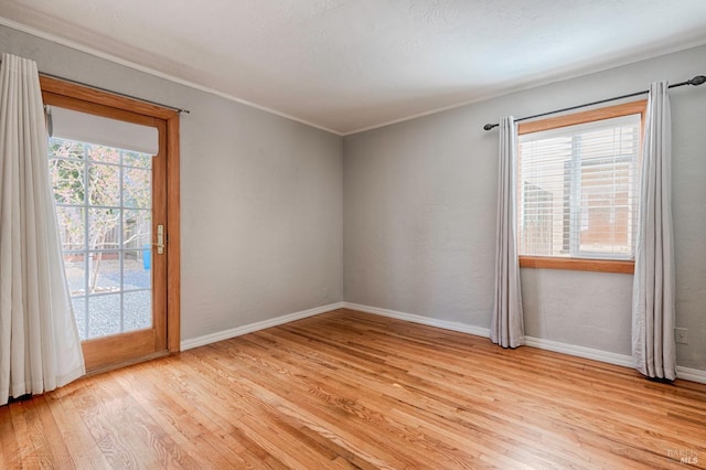 unfurnished room with baseboards, ornamental molding, light wood-type flooring, and a healthy amount of sunlight