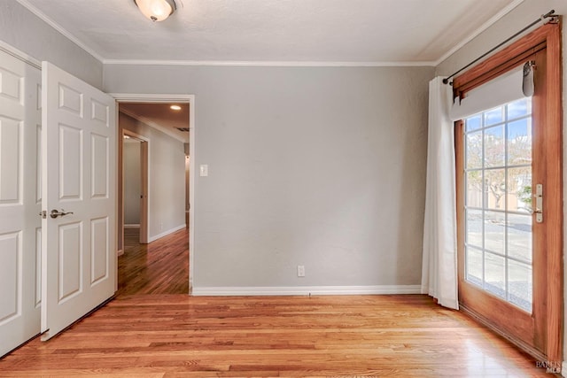 spare room featuring crown molding, light wood-style flooring, and baseboards