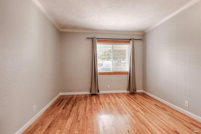 spare room featuring ornamental molding, light wood-type flooring, a textured ceiling, and baseboards