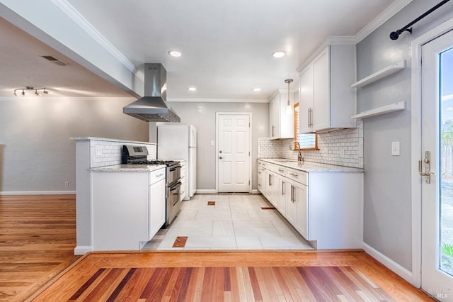 kitchen with visible vents, crown molding, wall chimney range hood, double oven range, and a sink