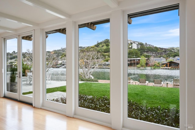 doorway to outside featuring beam ceiling, a water view, and wood finished floors