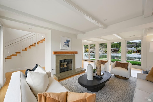 living room with a wealth of natural light, beam ceiling, a glass covered fireplace, and wood finished floors