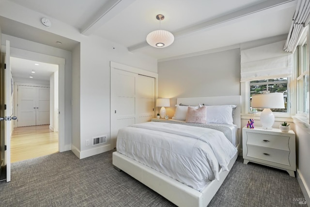 bedroom featuring beamed ceiling, a closet, visible vents, and baseboards