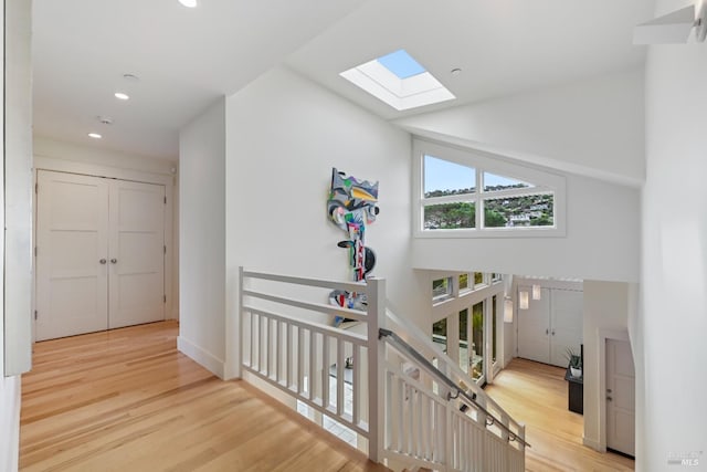 hallway featuring high vaulted ceiling, recessed lighting, an upstairs landing, and wood finished floors