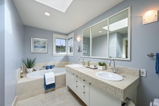 bathroom featuring a skylight, a garden tub, a sink, and double vanity