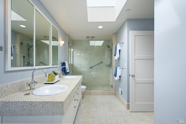 full bath featuring double vanity, a skylight, a sink, and a shower stall