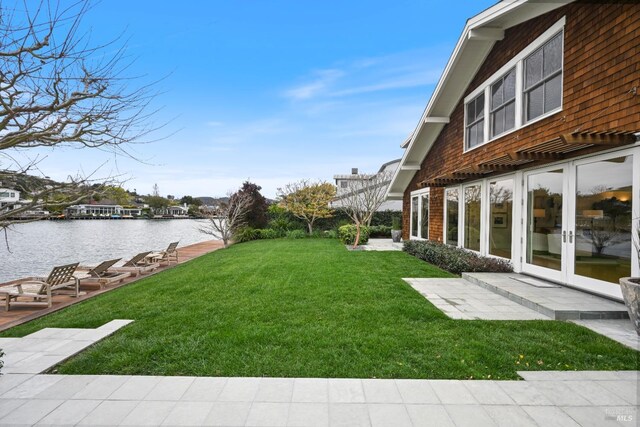 view of yard with a water view, a patio, and french doors