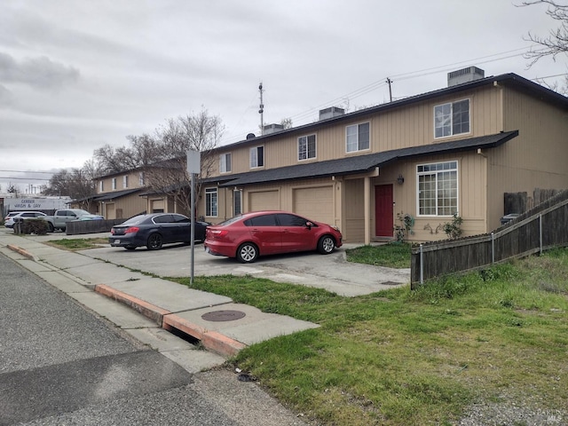 view of front facade with a garage, driveway, central AC unit, and fence