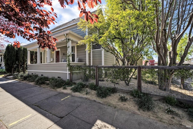 view of property exterior featuring a fenced front yard, crawl space, and covered porch