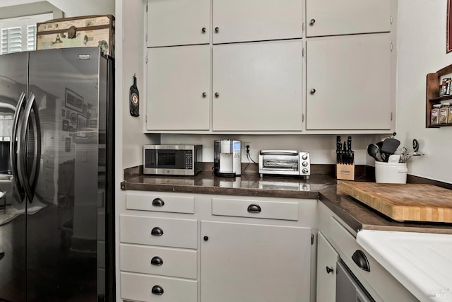 kitchen with dark countertops, a toaster, white cabinetry, and stainless steel appliances