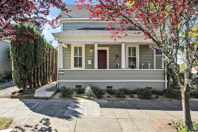 view of front of property featuring roof with shingles, a porch, crawl space, and a fenced front yard