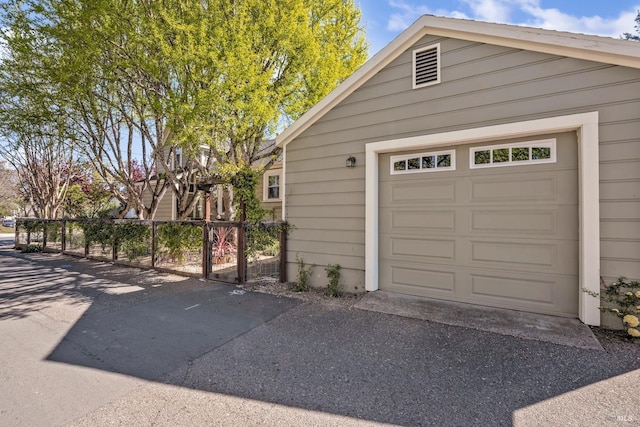 garage with aphalt driveway and fence