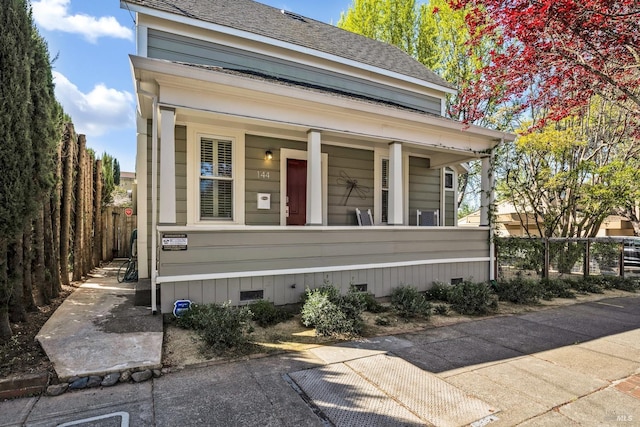 view of front facade with covered porch, roof with shingles, crawl space, and a fenced front yard