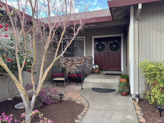 doorway to property with brick siding and fence