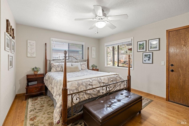 bedroom with light wood-type flooring, multiple windows, and a textured ceiling