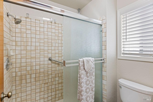 bathroom featuring a stall shower and toilet