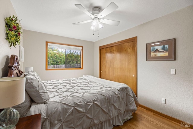 bedroom with ceiling fan, a textured wall, baseboards, a closet, and light wood-type flooring